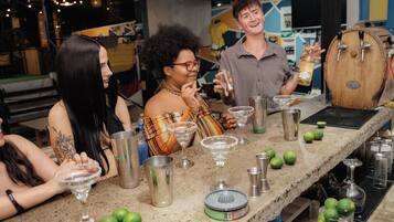 Uma área de bar com um balcão comprido, diversos utensílios e garrafas.