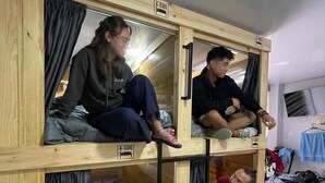 Una camera in stile dormitorio con letti a castello, pareti in legno e pavimento piastrellato.