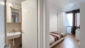 Ein Hotelzimmer mit einem Bett, einem Nachttisch, einem Spiegel und einem Fenster mit Vorhängen.