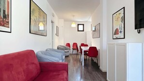 Un salon moderne avec des canapés rouges et gris, un coin repas avec des chaises rouges et des œuvres d’art accrochées aux murs.