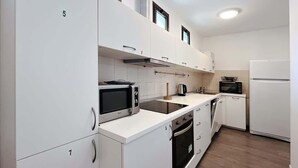 Een moderne keuken met witte kasten, een magnetron, een broodrooster en een koelkast.