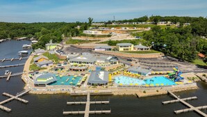 Luftaufnahme eines Ferienresorts am Wasser mit mehreren Pools, einem Hafen und verschiedenen Gebäuden.