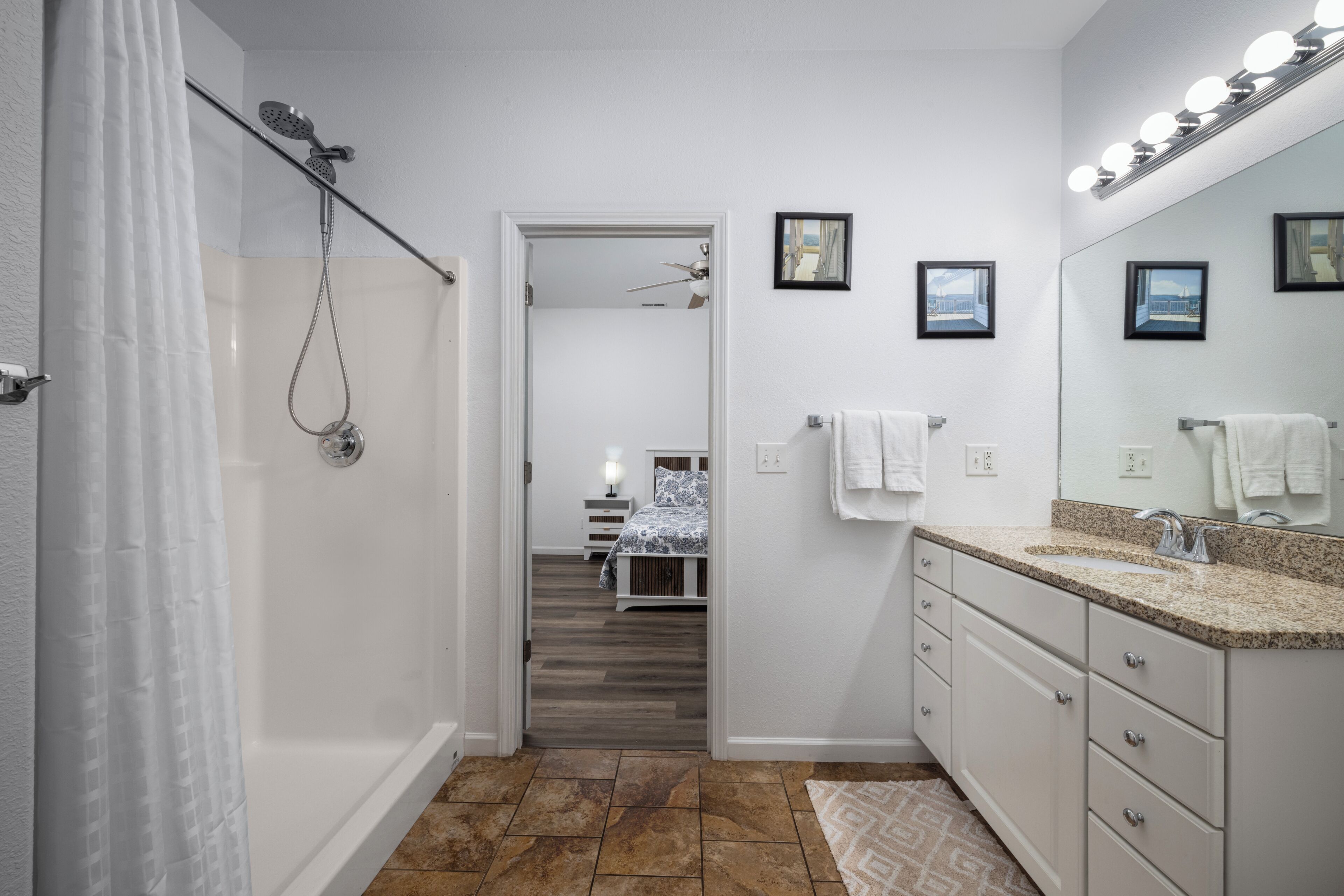 A bathroom with a shower, vanity, and a mirror with lights.