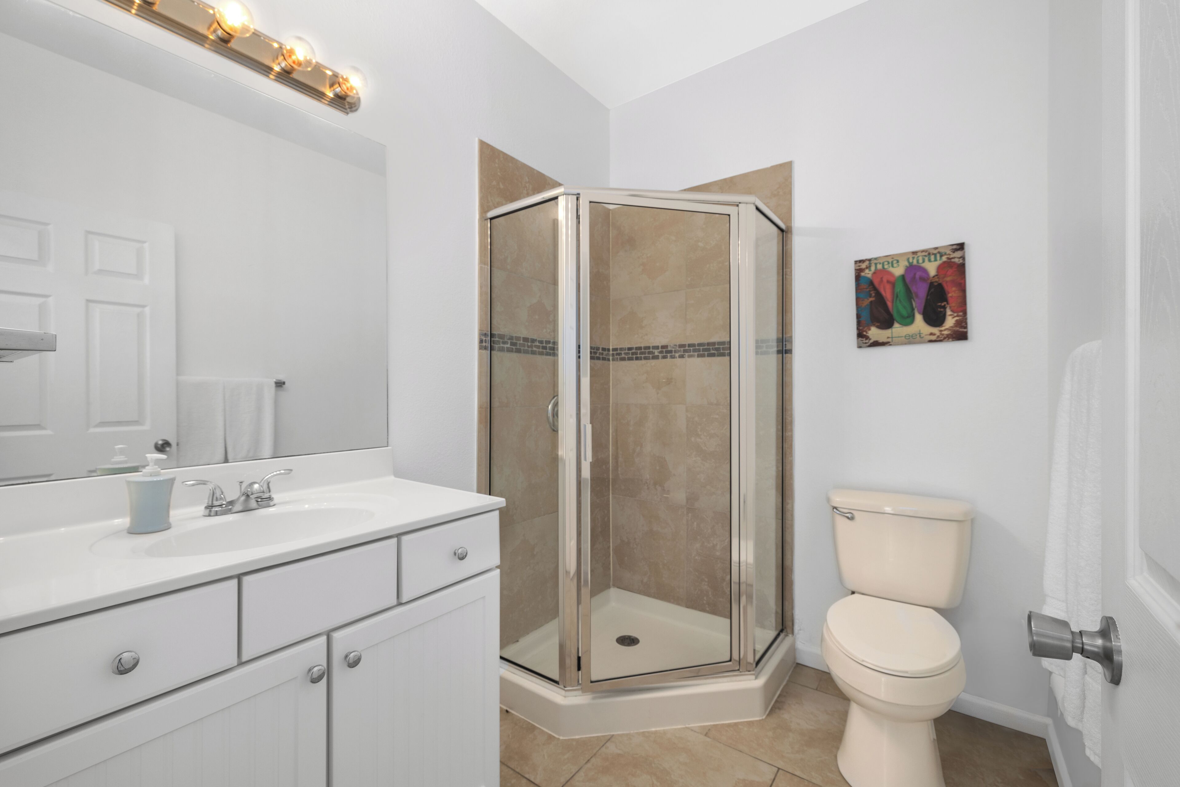 A modern bathroom with a glass-enclosed shower, a white sink with a mirror, and a toilet.