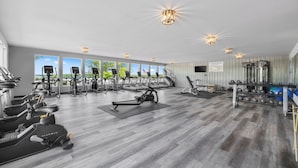 Ein großzügiger Fitnessraum mit unterschiedlichen Trainingsgeräten, großen Fenstern mit Blick und einem sauberen, modernen Design.