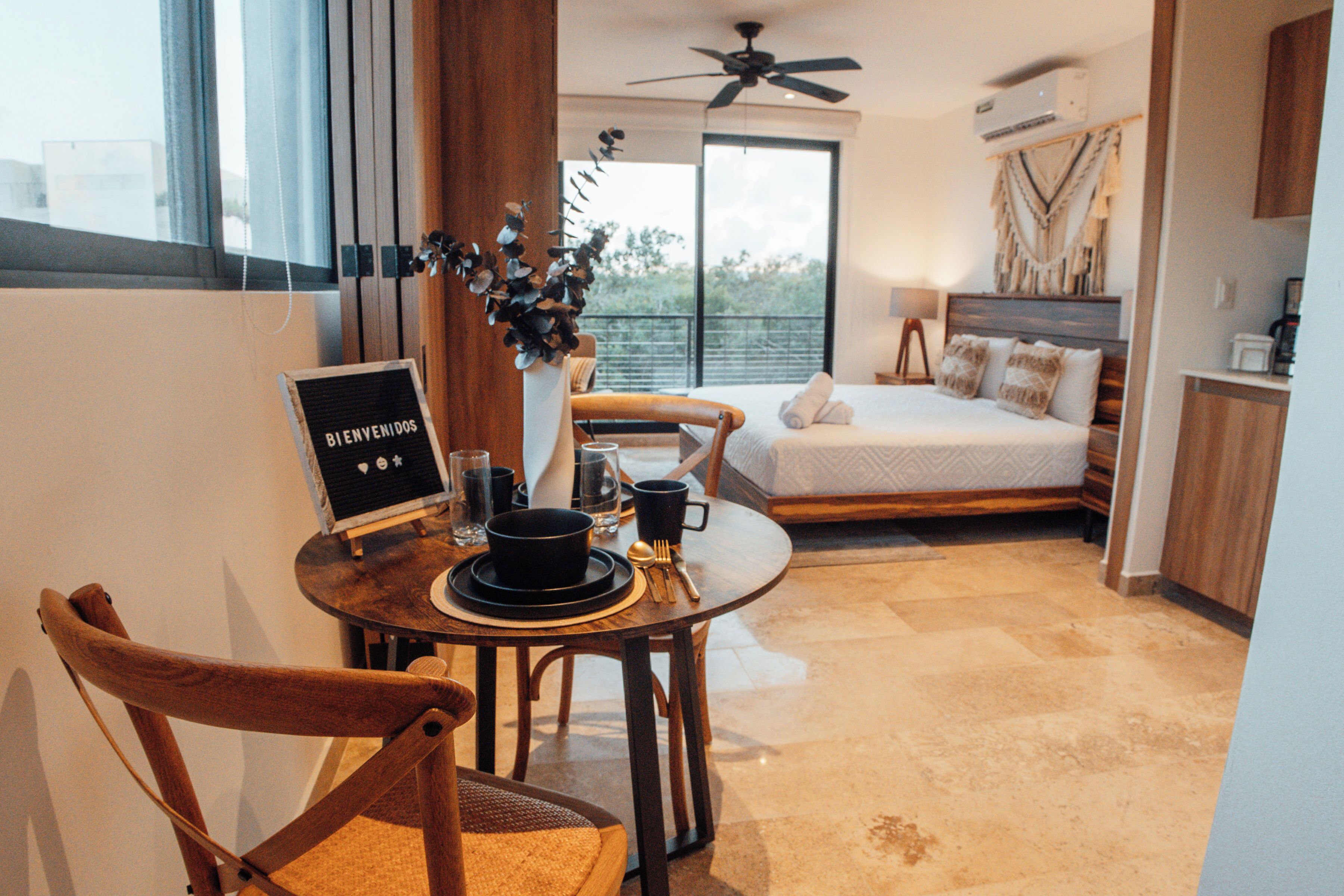 Una habitación de hotel moderna con zona de comedor, cama con vistas y balcón.