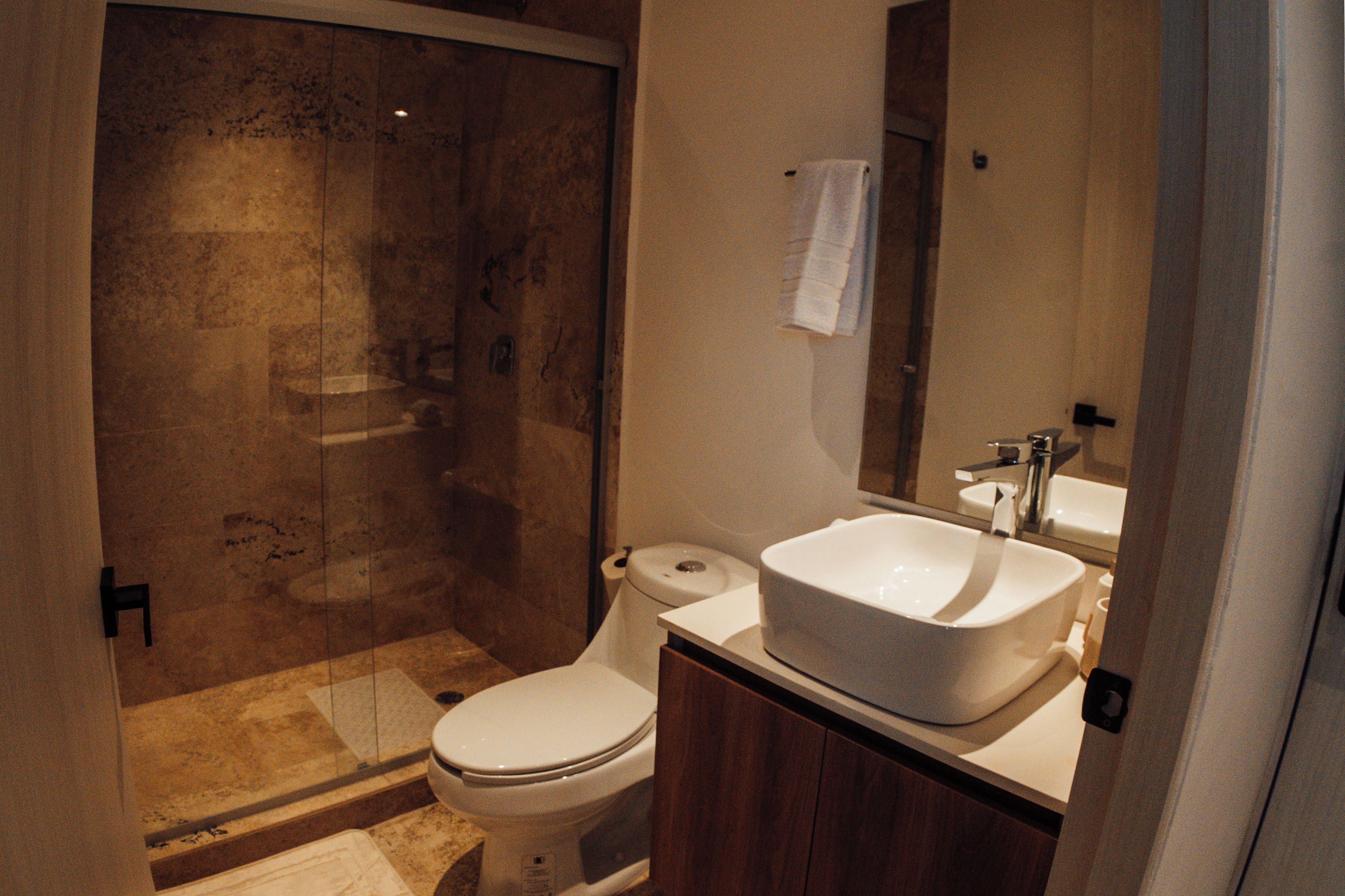 Une salle de bain avec une douche à parois de verre, des toilettes et un lavabo avec un miroir au-dessus.