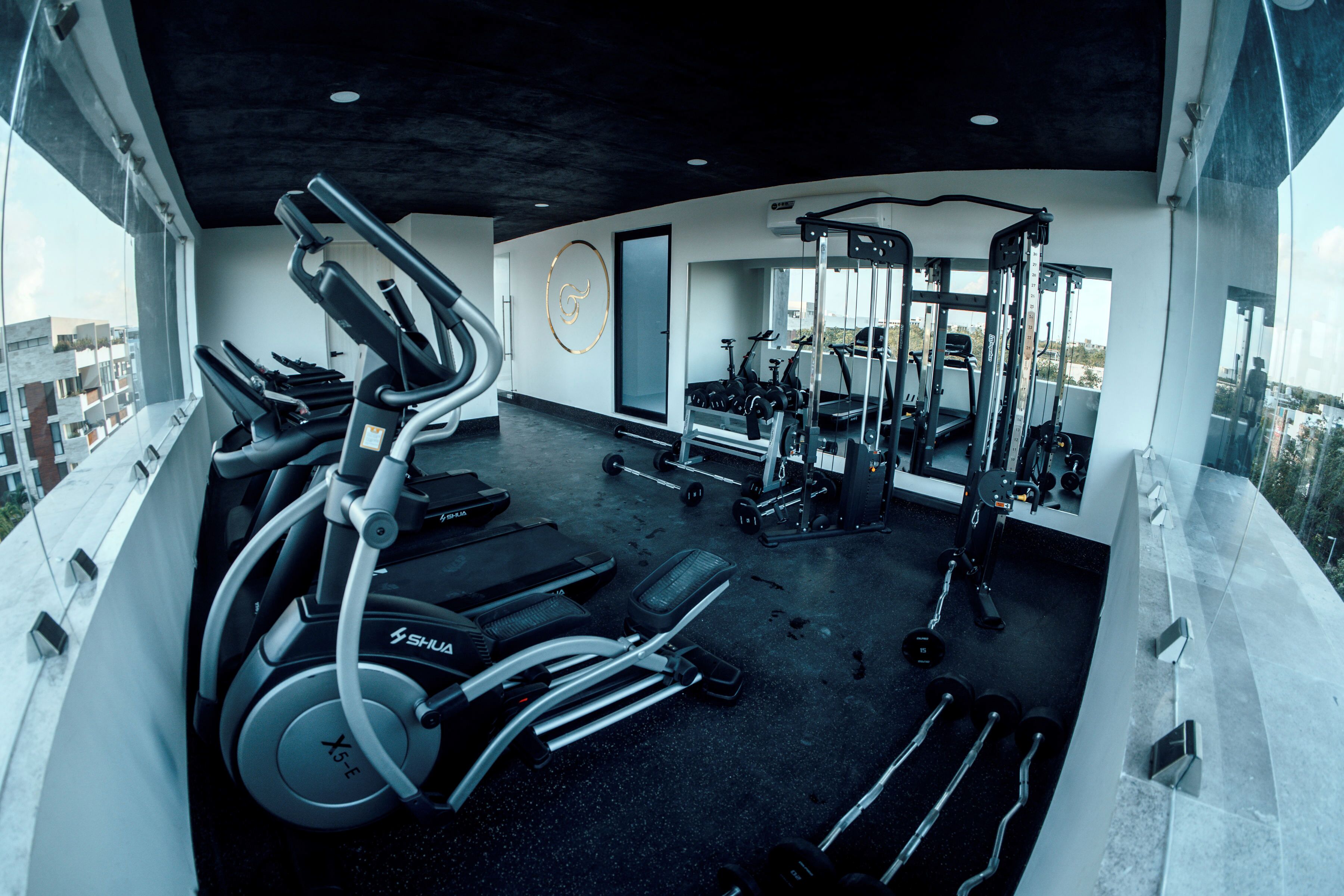 Un gimnasio con cintas de correr, elípticas y equipo de pesas.