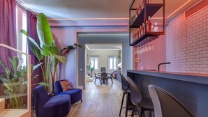Ein modernes Wohnzimmer mit einem blauen Sofa, einem Essbereich mit Tisch und Stühlen sowie einer Küche mit Backsteinwand und Regalen.