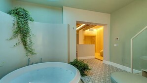 Ein modernes Badezimmer mit einer freistehenden Badewanne, einer Duschkabine und einer sichtbaren Tür zu einem anderen Raum.