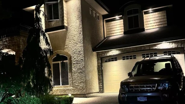 Uma casa de dois andares com garagem, entrada para carros e um SUV estacionado.