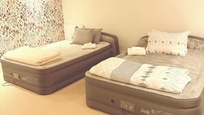 Quarto com duas camas, cada uma com colchão Sealy, parede estampada e teto liso.