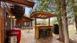 Een houten terras met een bar, zitplaatsen buiten en een Coca-Cola koeler.