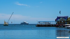 Un port de plaisance avec des bateaux, une jetée et un panneau sur lequel on peut lire : « ALLEZ PLUS LOIN ».