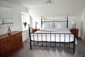 A bedroom with a metal bed frame, a wooden dresser, a mirror, and two bedside tables with lamps.