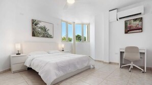 A bedroom with a bed, bedside tables, a desk, and a chair. - Beachfront by Otium | Pool | BBQ | Beach Access (Río Grande)