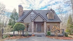 A two-story house with a stone chimney, a front porch, and a garage.
