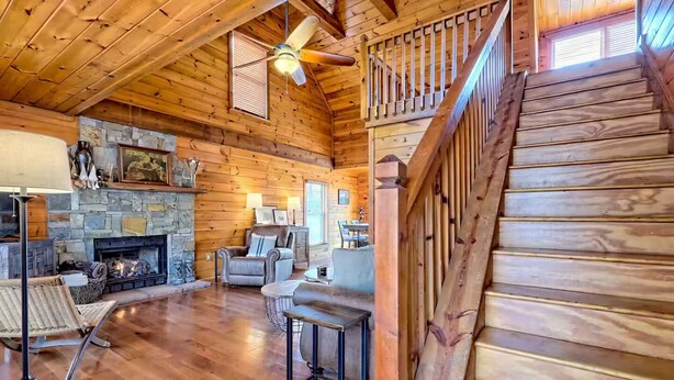 A spacious wooden interior with a fireplace, comfortable seating, and a staircase.