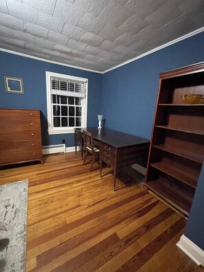 A room with a wooden floor, a dining table with chairs, a window with blinds, a dresser, and a bookshelf. - Spacious 6-bedroom country house in lovely Ellerbe on 55 private acres of forest (Ellerbe)
