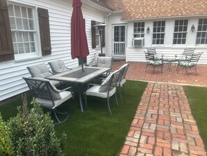 A patio with a table and chairs, a red umbrella, and a brick pathway. - Spacious 6-bedroom country house in lovely Ellerbe on 55 private acres of forest (Ellerbe)