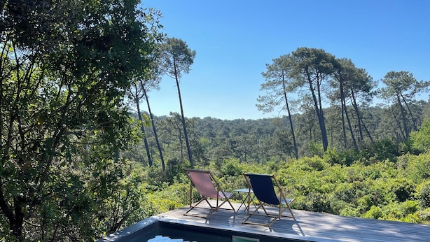 Une piscine aux eaux cristallines, dotée d’une terrasse en bois et de deux chaises longues.