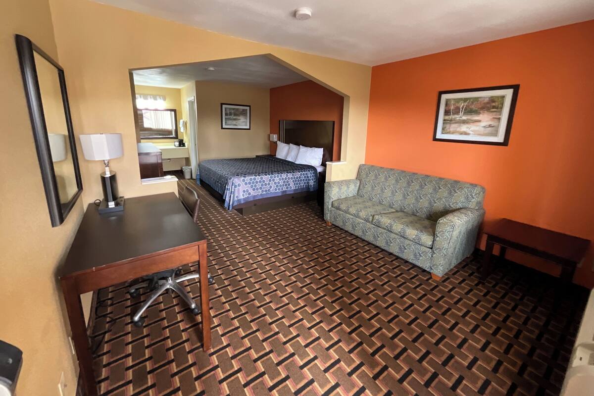 A hotel room with a bed, a sofa, a desk, and a chair.