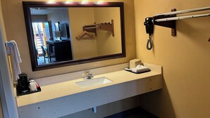 Une salle de bain d’hôtel équipée d’un lavabo, d’un miroir, d’un porte-serviettes et d’un téléphone.