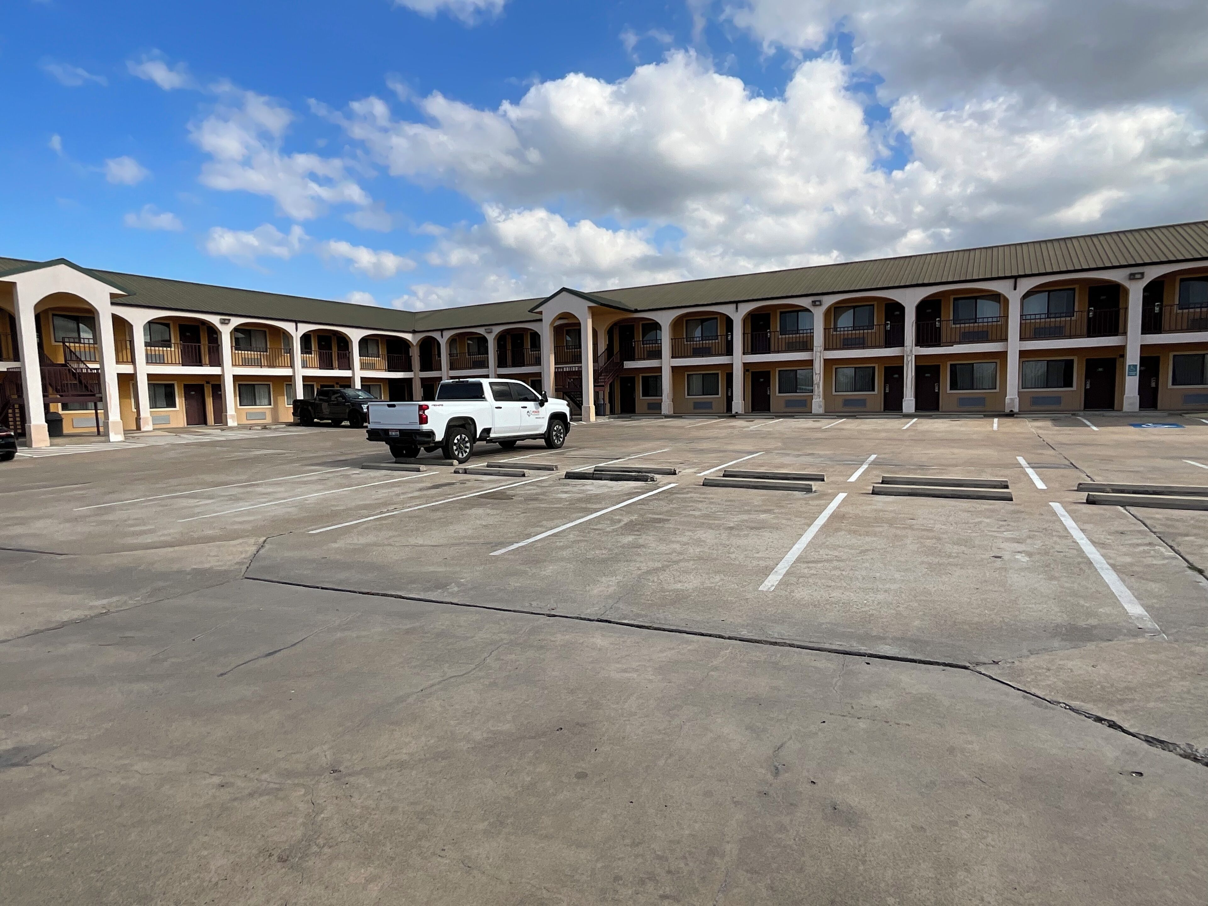 A motel with a large parking lot and multiple balconies.