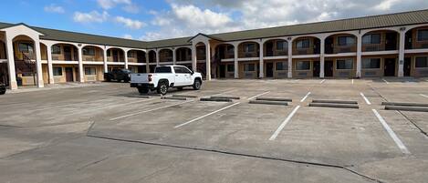 A motel with a large parking lot and multiple balconies.