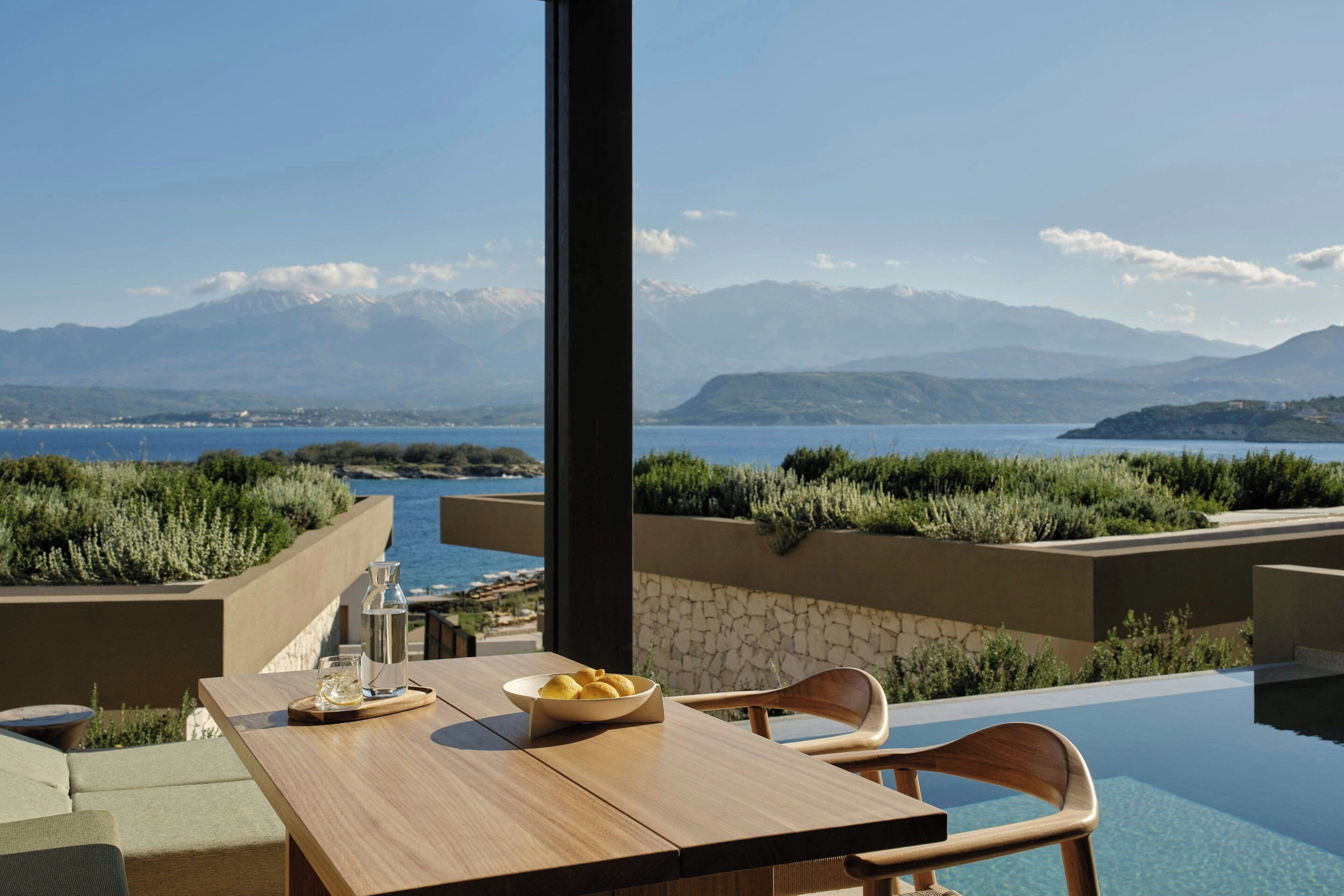 An outdoor dining area with a view of mountains and a body of water.