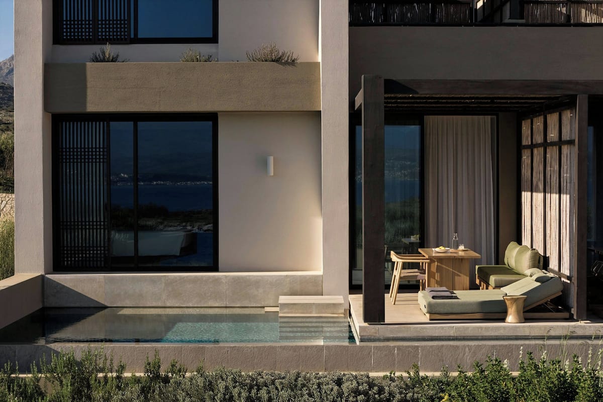 Una casa moderna con piscina, mobiliario de exterior y amplias ventanas.