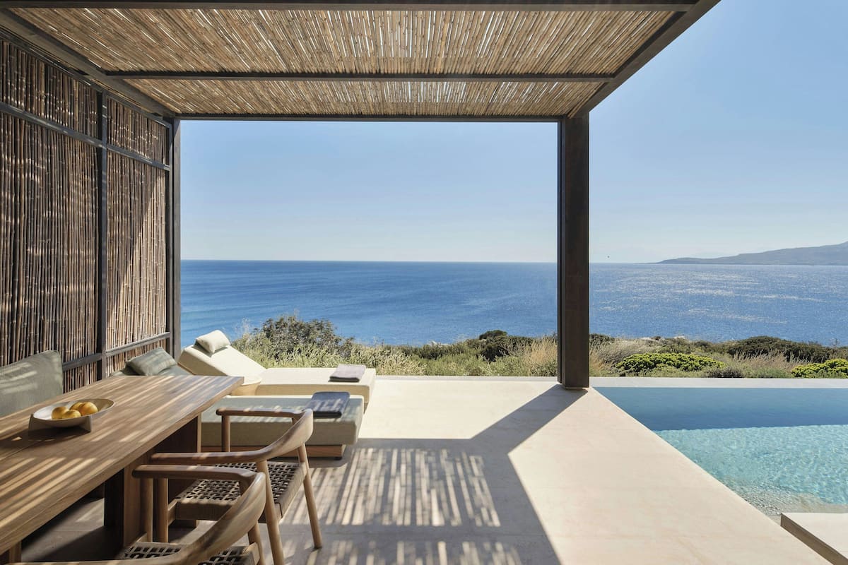 Un área lounge moderna al aire libre con piscina, asientos y vistas al mar.