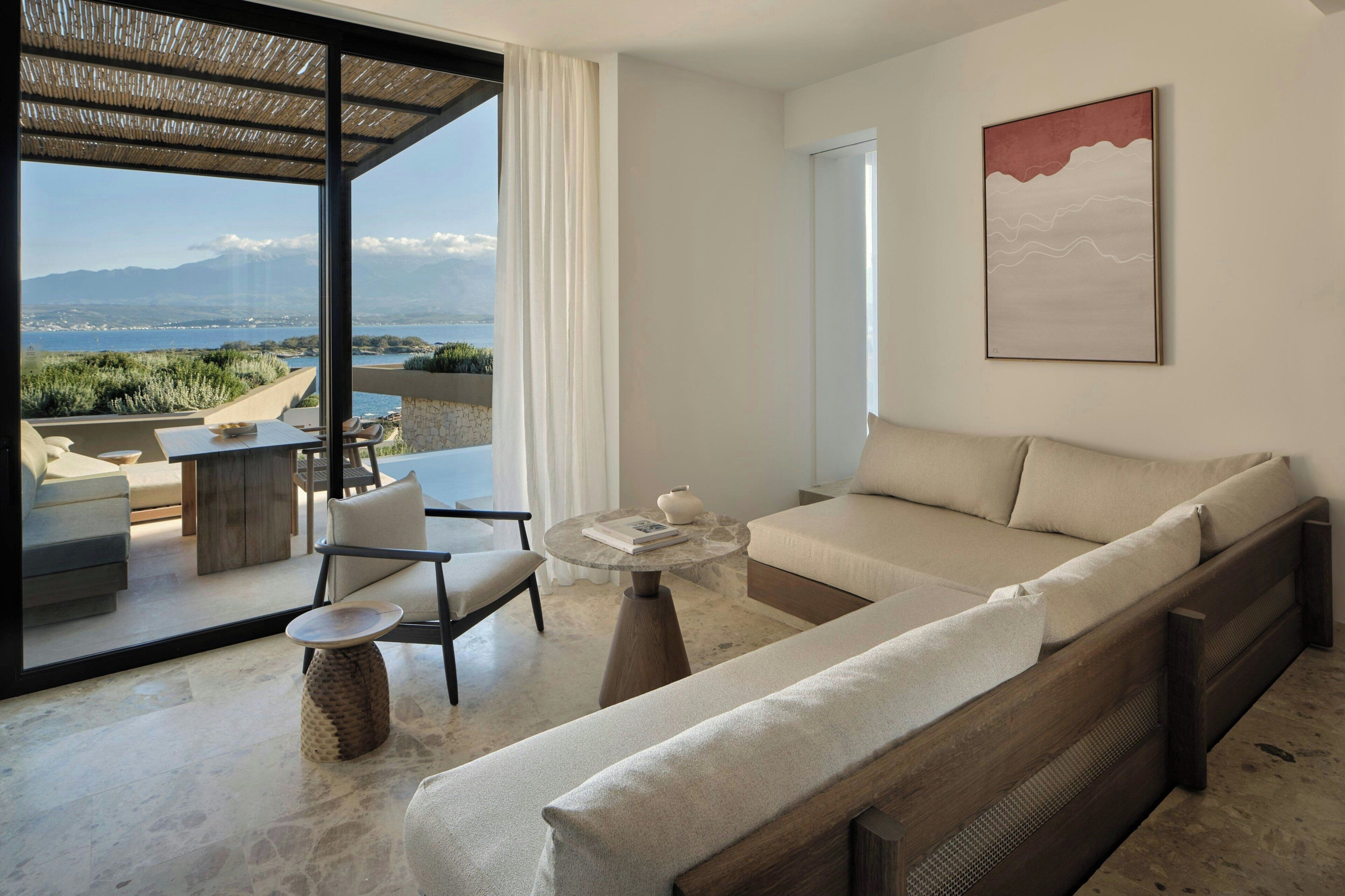 A modern living room with a sofa, chairs, a coffee table, and a view of the outdoors.