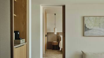 Una habitación de hotel moderna con un armario de madera, suelo de baldosas de mármol, lámpara colgante y una obra de arte enmarcada en la pared.