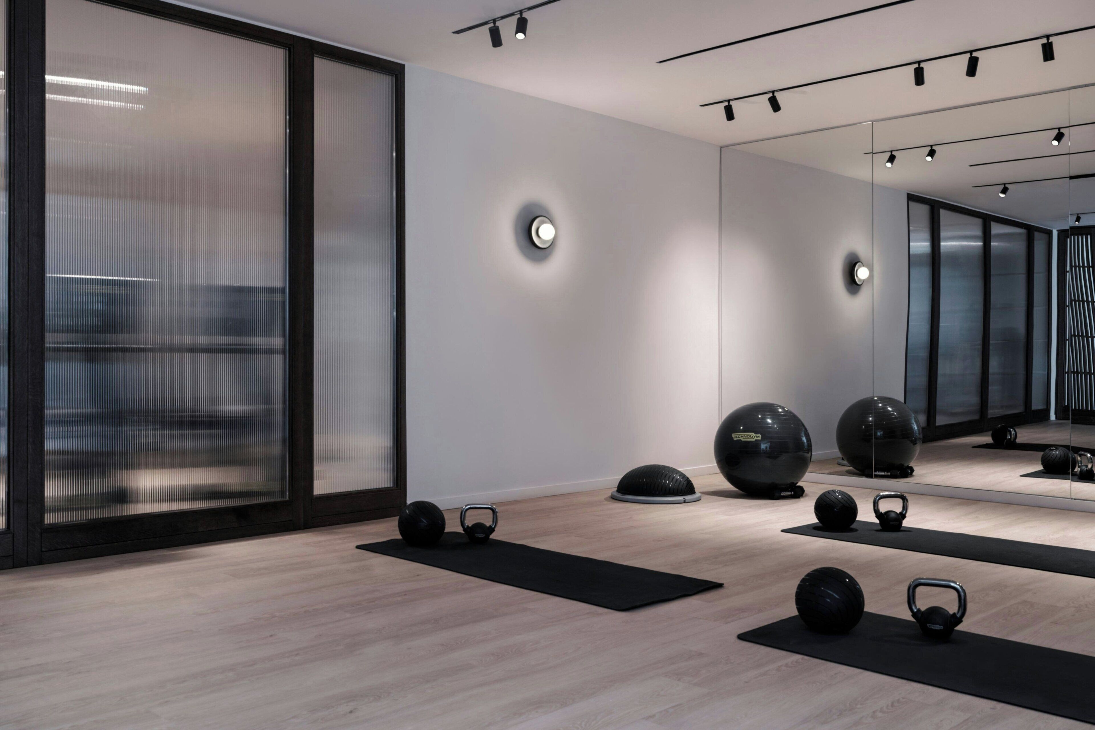 Ein modernes, minimalistisches Fitnessstudio mit Trainingsgeräten und großen Fenstern.