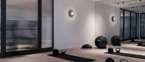 Ein modernes, minimalistisches Fitnessstudio mit Trainingsgeräten und großen Fenstern.