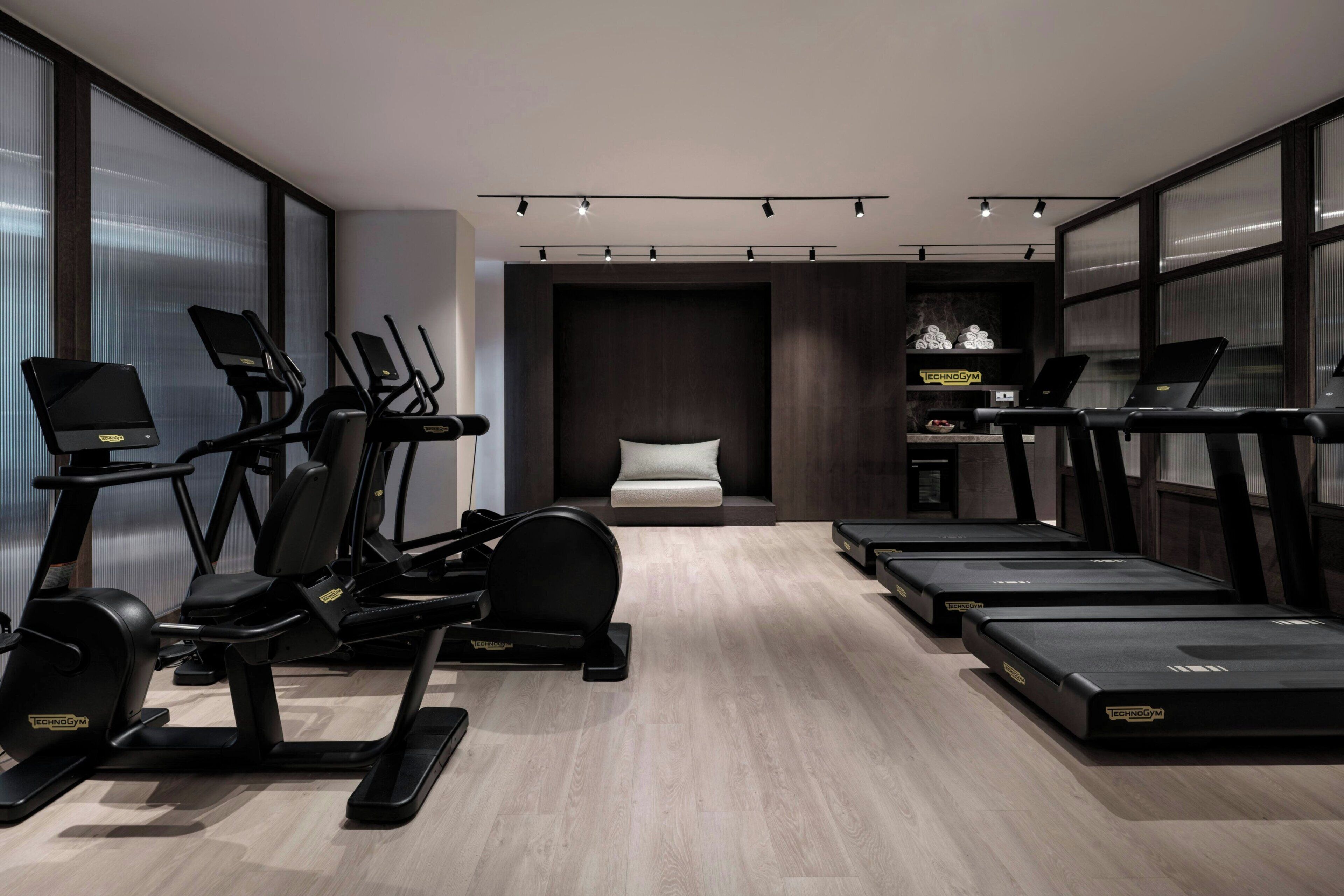A modern gym with multiple treadmills, stationary bikes, and elliptical machines.