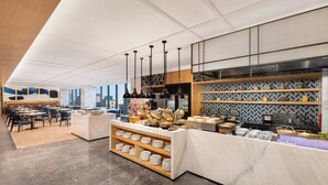 Un comedor moderno con una mesa de buffet, que incluye un mostrador con alimentos y una vajilla en exhibición.