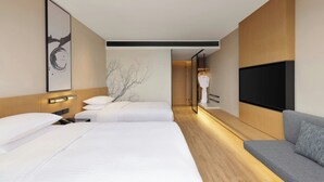 Una habitación de hotel moderna con una cama grande, un sofá, un televisor de pantalla plana y una obra de arte colgada en la pared.