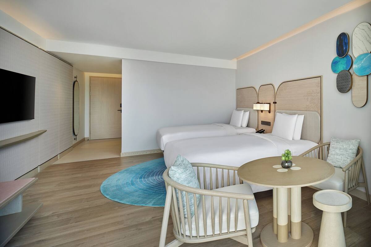A hotel room with a bed, bedside table, chair, and a TV.