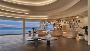 A modern lobby with a view of the sea, featuring a wooden reception desk, seating areas, and a ceiling with circular lighting. - Veranda Resort Phuket, Autograph Collection (Wichit)