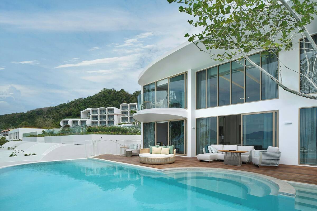 A modern house with a swimming pool, outdoor seating, and large windows.