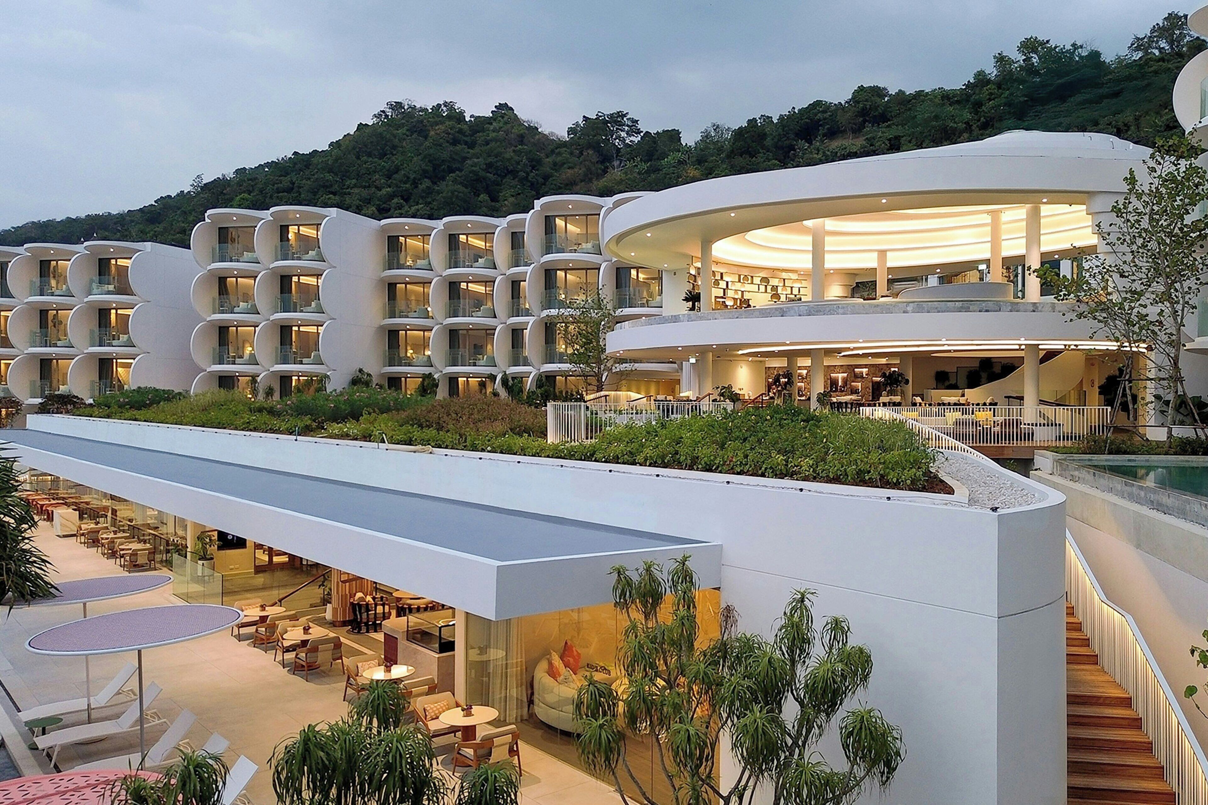 Un hotel moderno con varios balcones, zonas de estar al aire libre y una piscina.