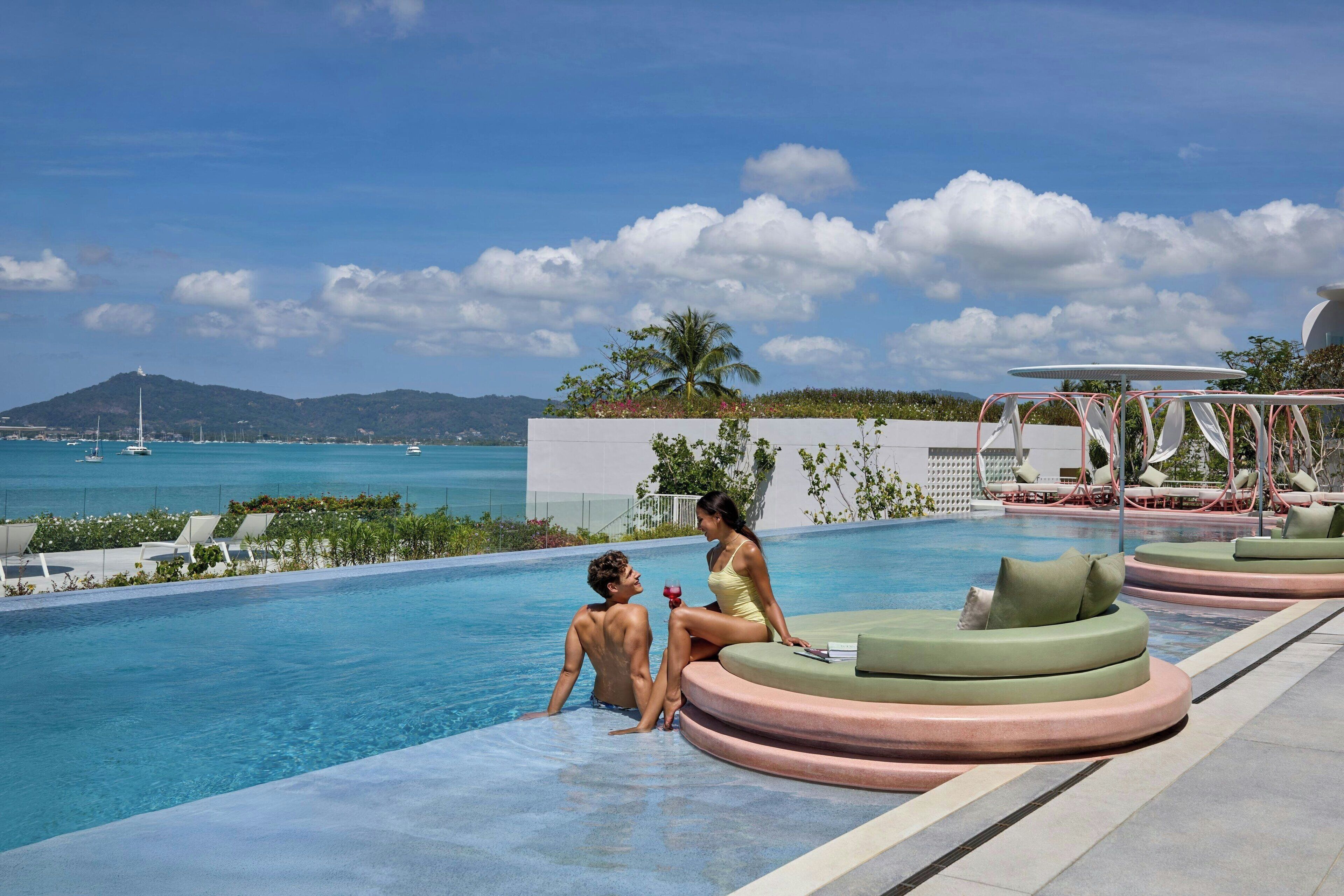A poolside area with lounge chairs and a view of the sea.