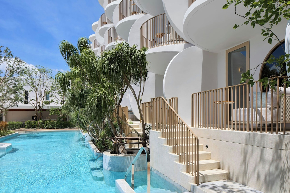 Un hotel moderno con piscina, escaleras exteriores y balcones.