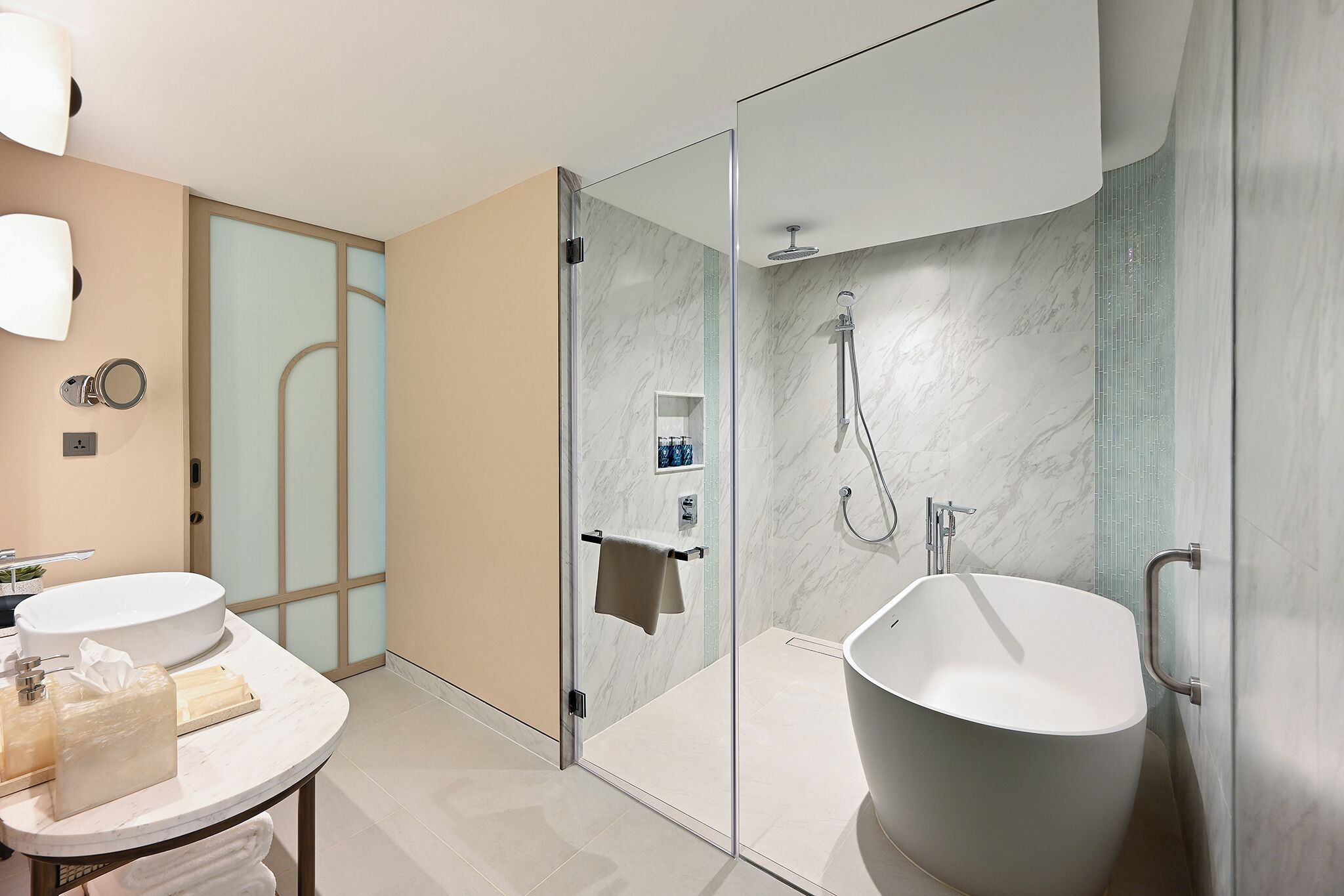 Une salle de bain moderne dotée d’une douche à parois de verre, d’une baignoire sur pieds et d’un meuble-lavabo rond avec un évier et un porte-serviettes.