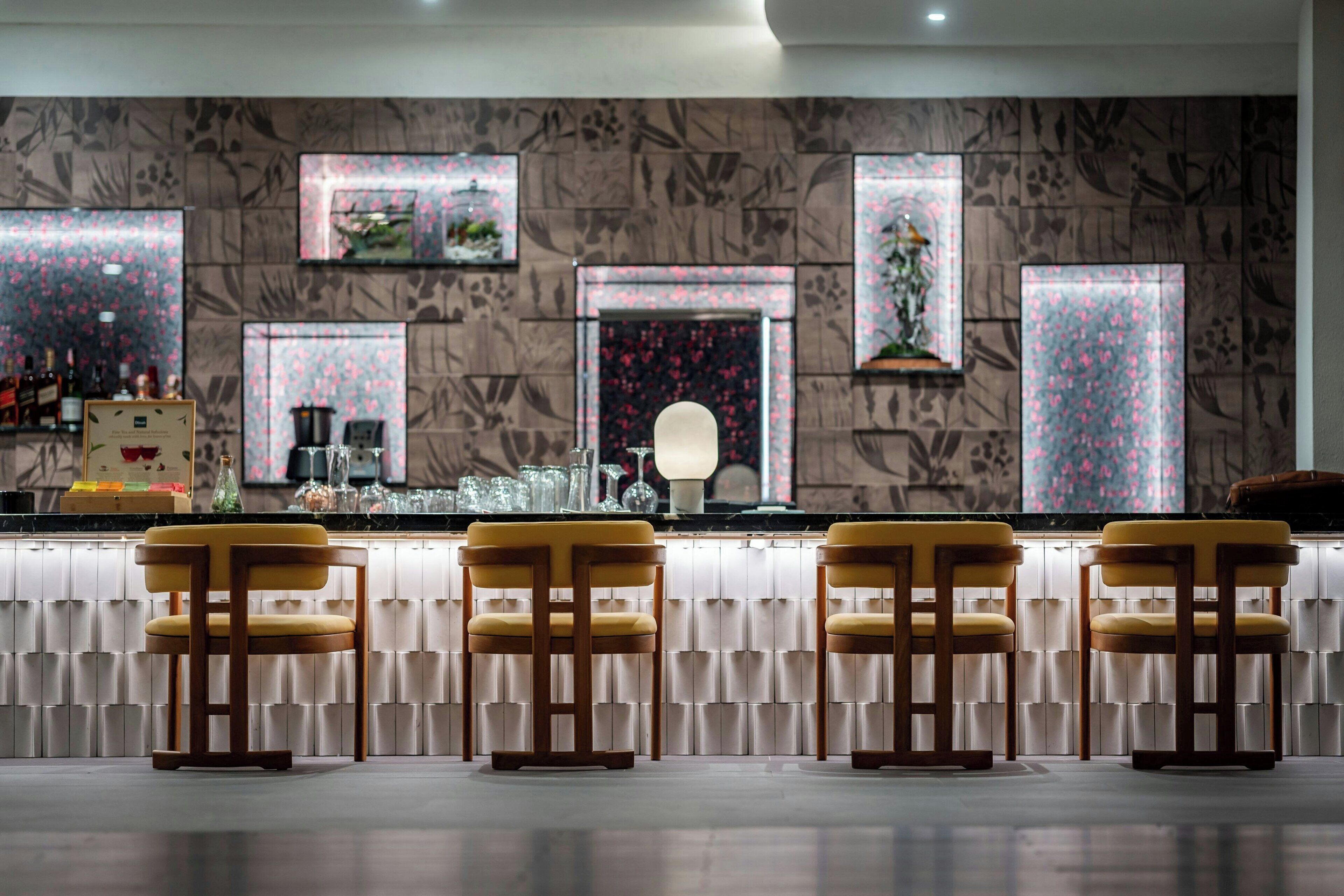 A bar area with three yellow bar stools, a counter with a mirror, and decorative wall panels.