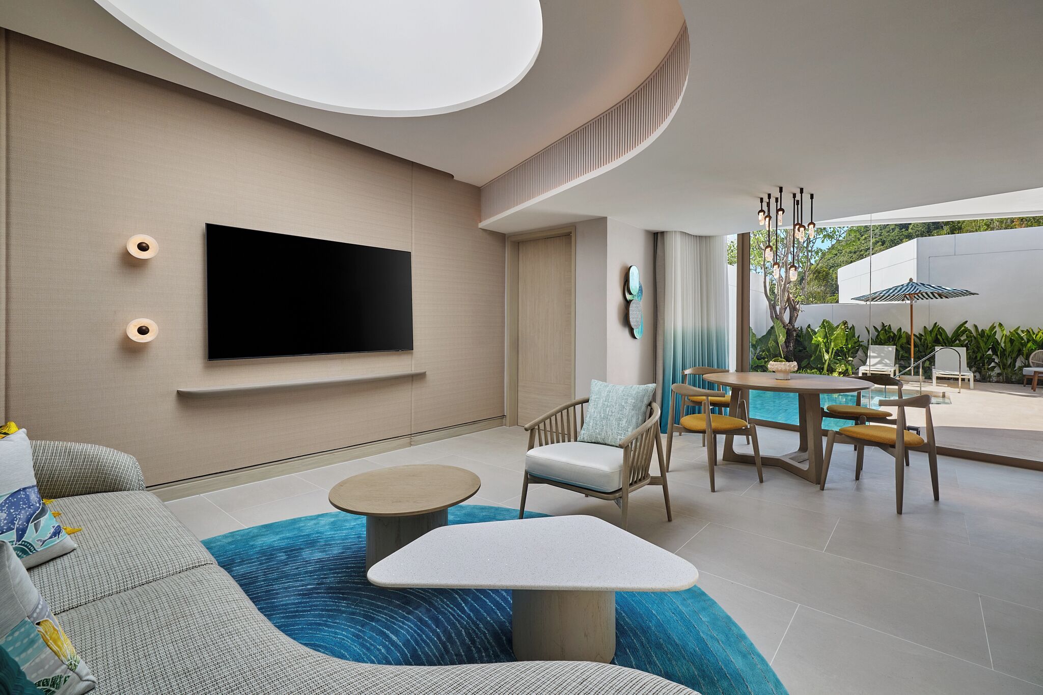 A modern living room with a flat-screen TV, comfortable seating, a pool table, and a dining area with outdoor seating.