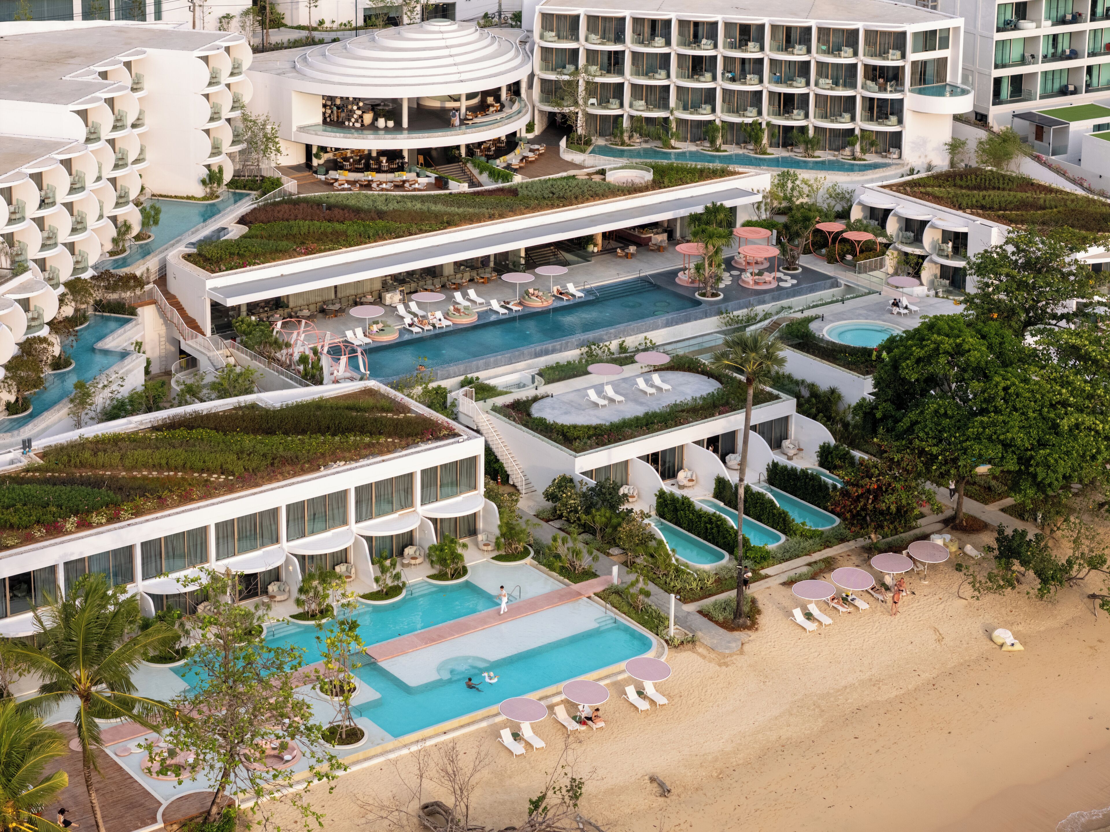 Un resort con varias piscinas, zonas de estar al aire libre y una playa.