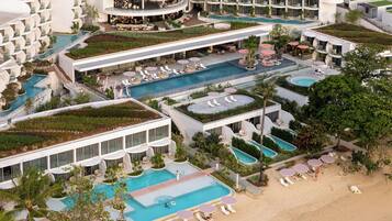 Un resort con varias piscinas, zonas de estar al aire libre y una playa.